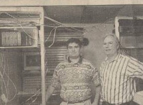 A young Jamie Dolan (left) and his father Tim Dolan standing in front of a rack of dial-up modems and cabling at the PowerNet offices in Menasha, 1998