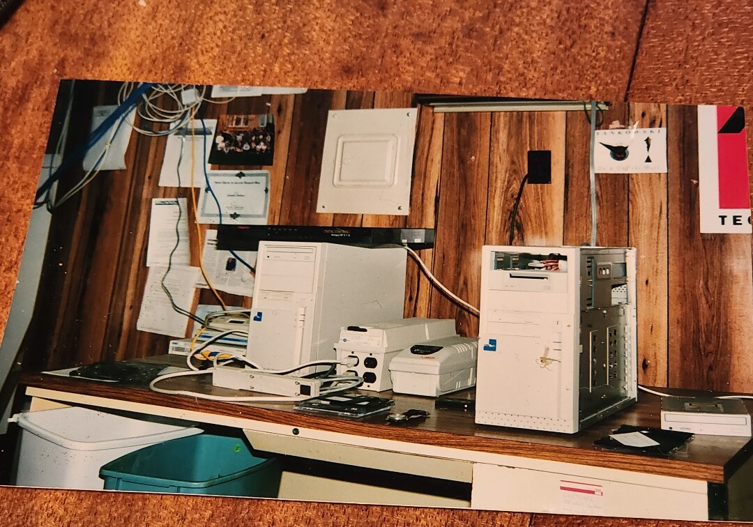 The early PowerNet server room around 1997: beige tower PCs, a modem bank, a network hub and cabling against a wood-paneled wall