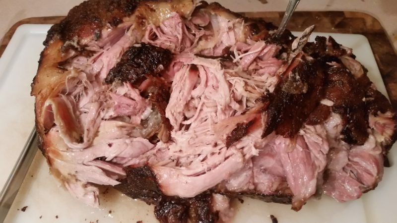 Smoked pork shoulder pulled apart on a cutting board, showing the pink smoke ring