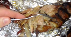 Tender smoked BBQ pork pulling apart with a fork inside foil