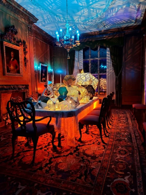 Period dining room bathed in blue and orange light with projections on the ceiling