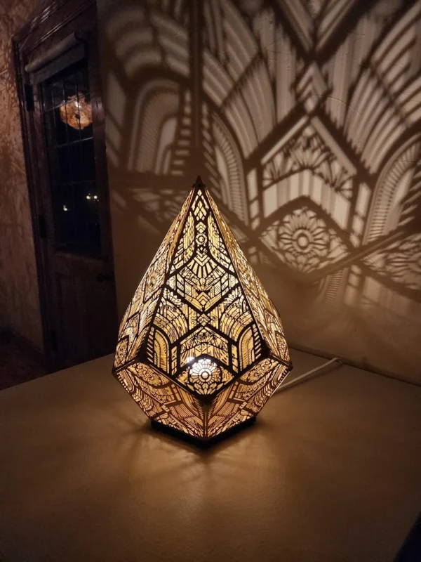 An ornate teardrop-shaped lamp casting lacework shadows on the wall