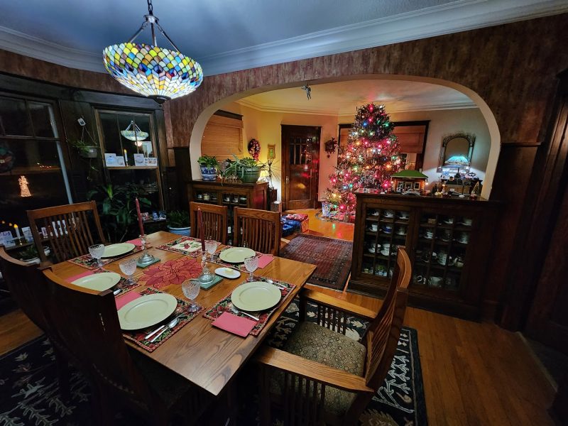 Historic Neenah dining room set for Christmas Eve dinner, with a stained-glass chandelier and a lit tree through the archway