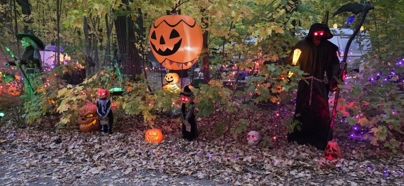 Halloween campsite display at dusk with a jack-o-lantern balloon, witch, and Grim Reaper