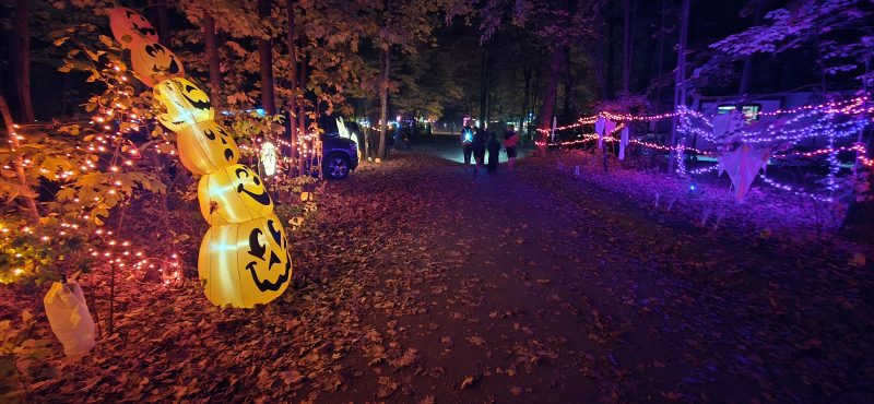 Stacked jack-o-lantern inflatable beside a string-lit campground path at night