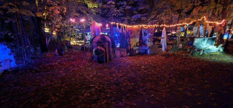 Campsite with a Happy Halloween banner, ghosts, and overhead string lights
