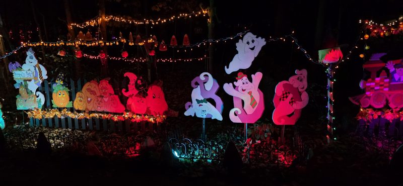 Row of friendly ghost and pumpkin plywood cutouts lit in red and orange